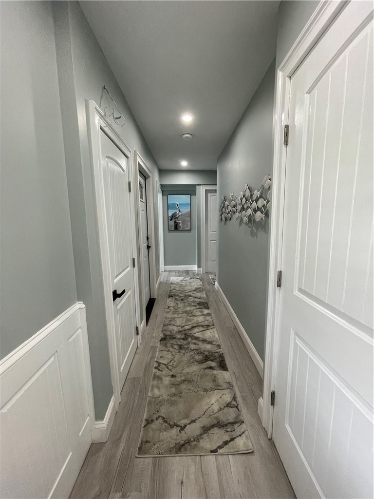 Hallway with white paneled doors, a marbled runner rug, and coastal fish wall decor.