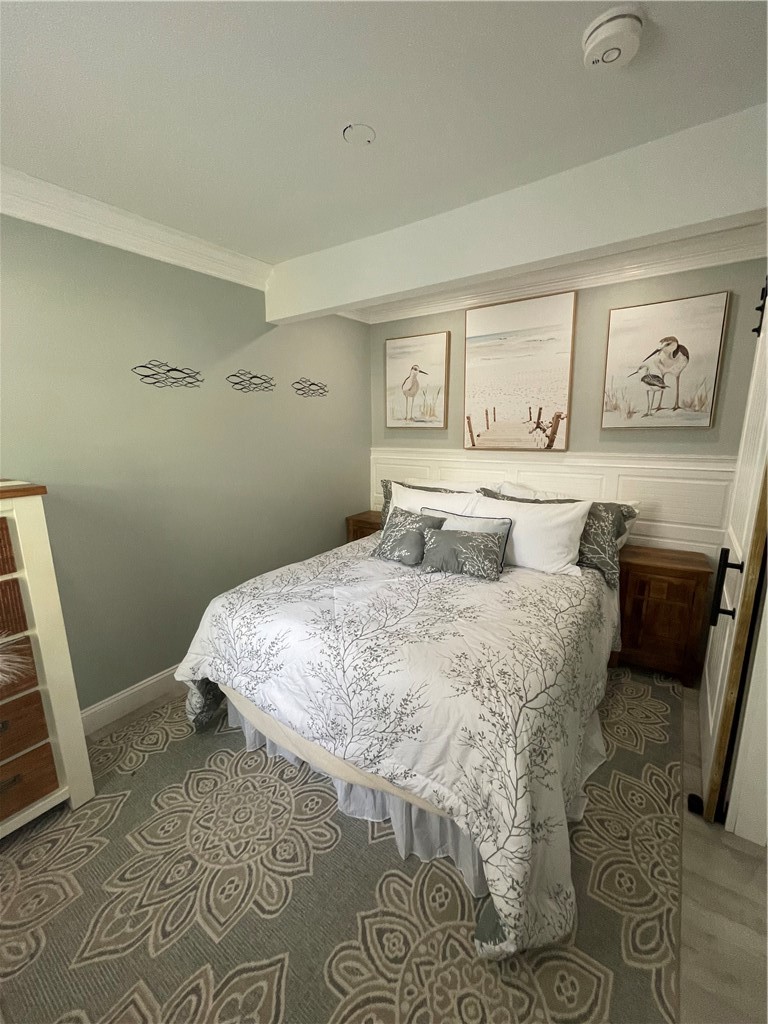 Bedroom with botanical-patterned bedding, coastal artwork, wooden nightstands, and a patterned rug.