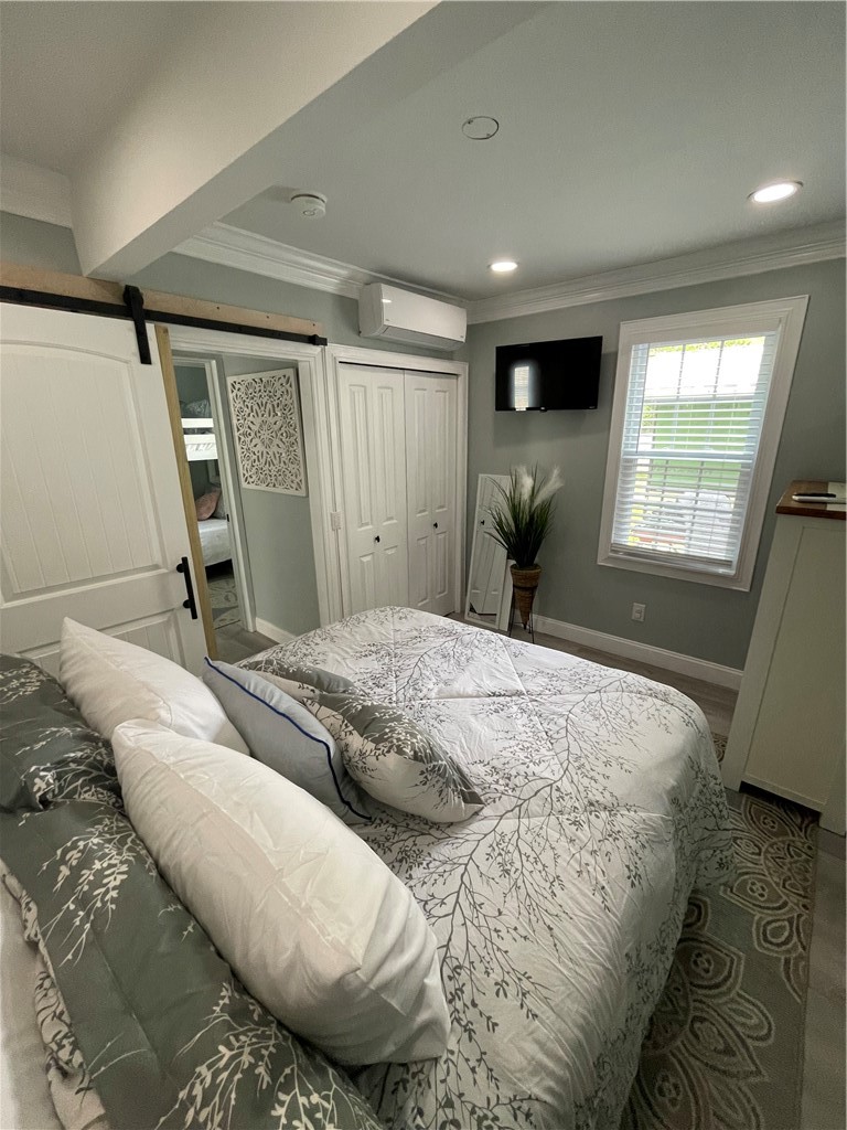 Furnished bedroom with botanical-patterned bedding, white paneled doors, and a window with blinds.
