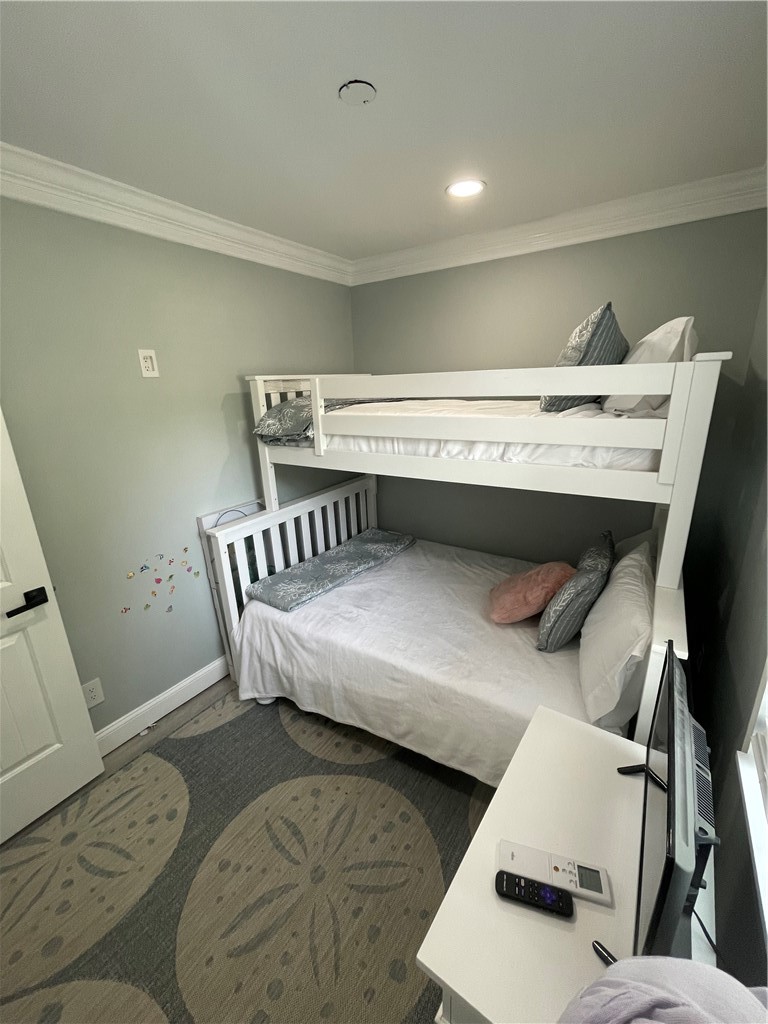 Bedroom with a white bunk bed, a lower bed, and a patterned rug.