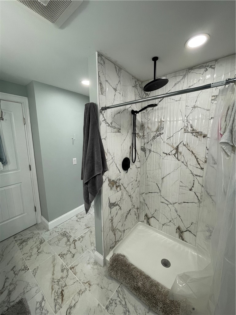 Bathroom with a marble-look walk-in shower, black fixtures, and matching veined floor tile.