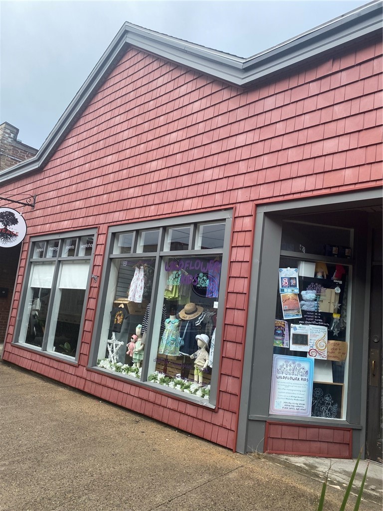 Red-shingled storefront with children’s clothing displays and a recessed entrance.