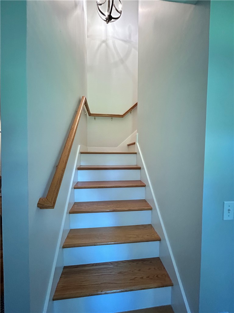 Staircase with wooden treads and handrail, white risers, and pale blue walls.