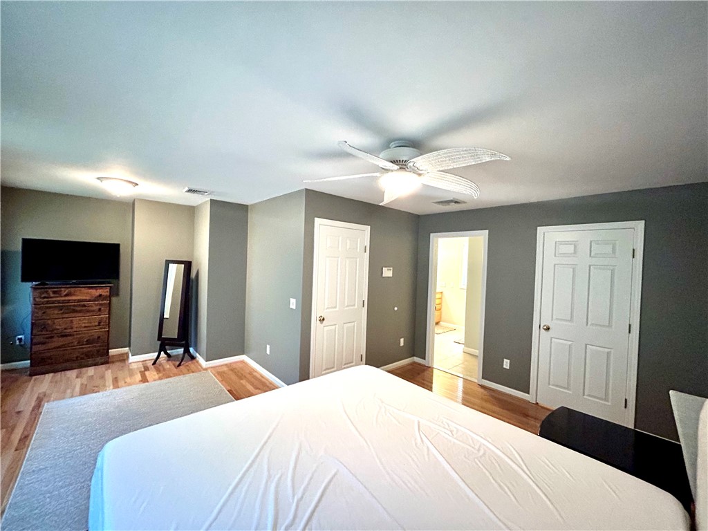 Bedroom with a ceiling fan, gray walls, hardwood floors, and a bed.