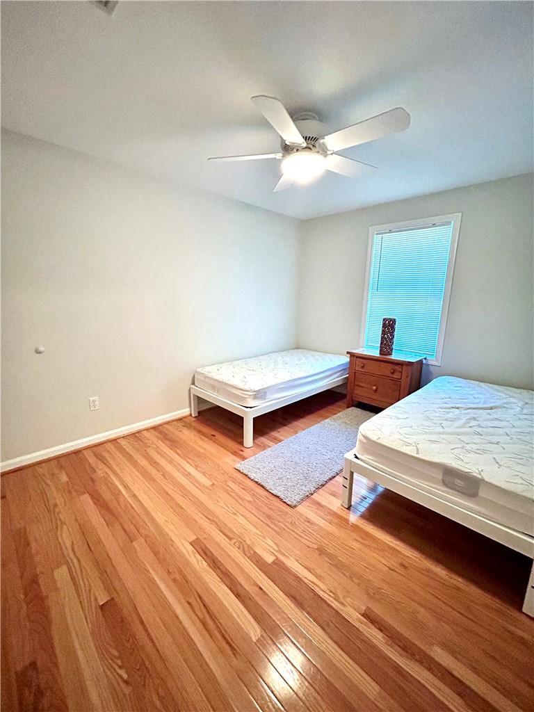 Bedroom with two single beds, hardwood floors, and a ceiling fan.