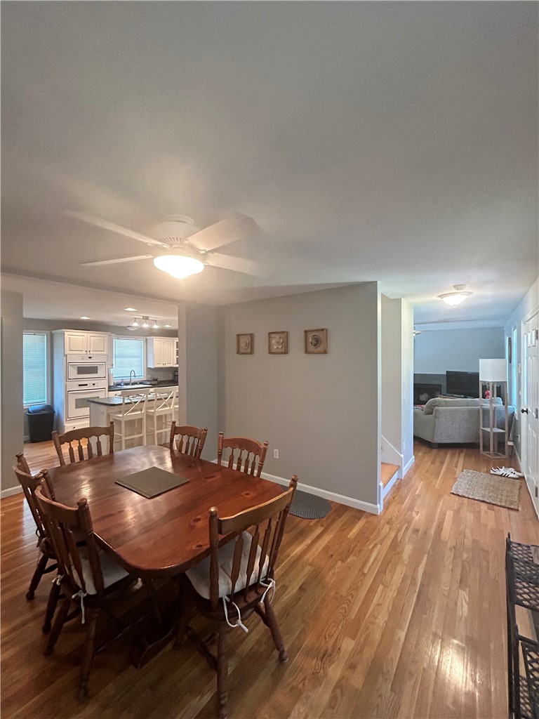 Dining area with a wooden table, open kitchen, and hardwood floors.