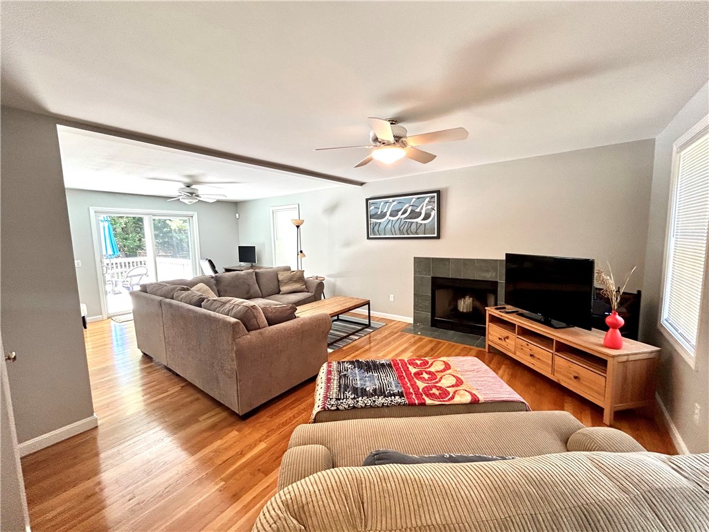 Living room with hardwood floors, a sectional sofa, tiled fireplace, and sliding doors to a deck.