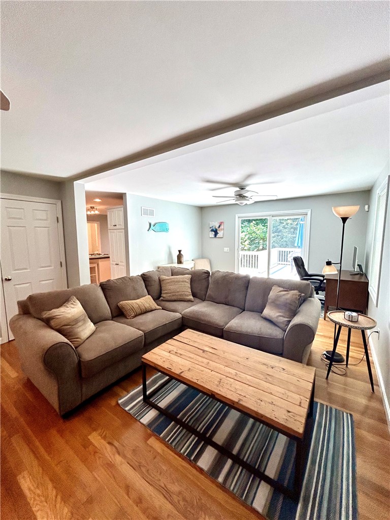 Living room with a gray sectional, wood coffee table, hardwood floors, and sliding doors to a deck.