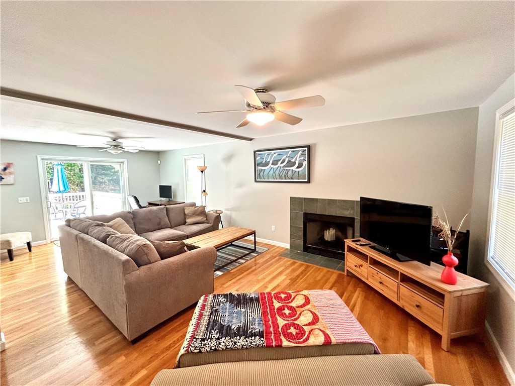 Living room with a gray sectional, tiled fireplace, hardwood floors, and sliding glass doors to a deck.