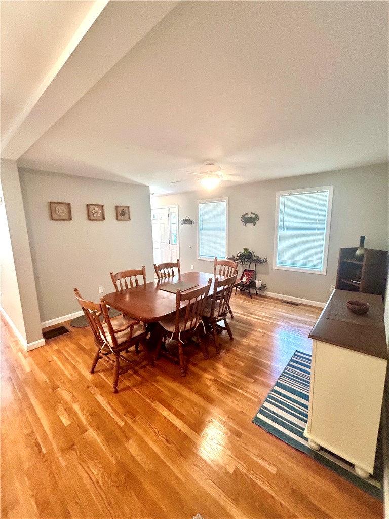 Dining room with a wooden table, hardwood floors, and two windows with blinds.