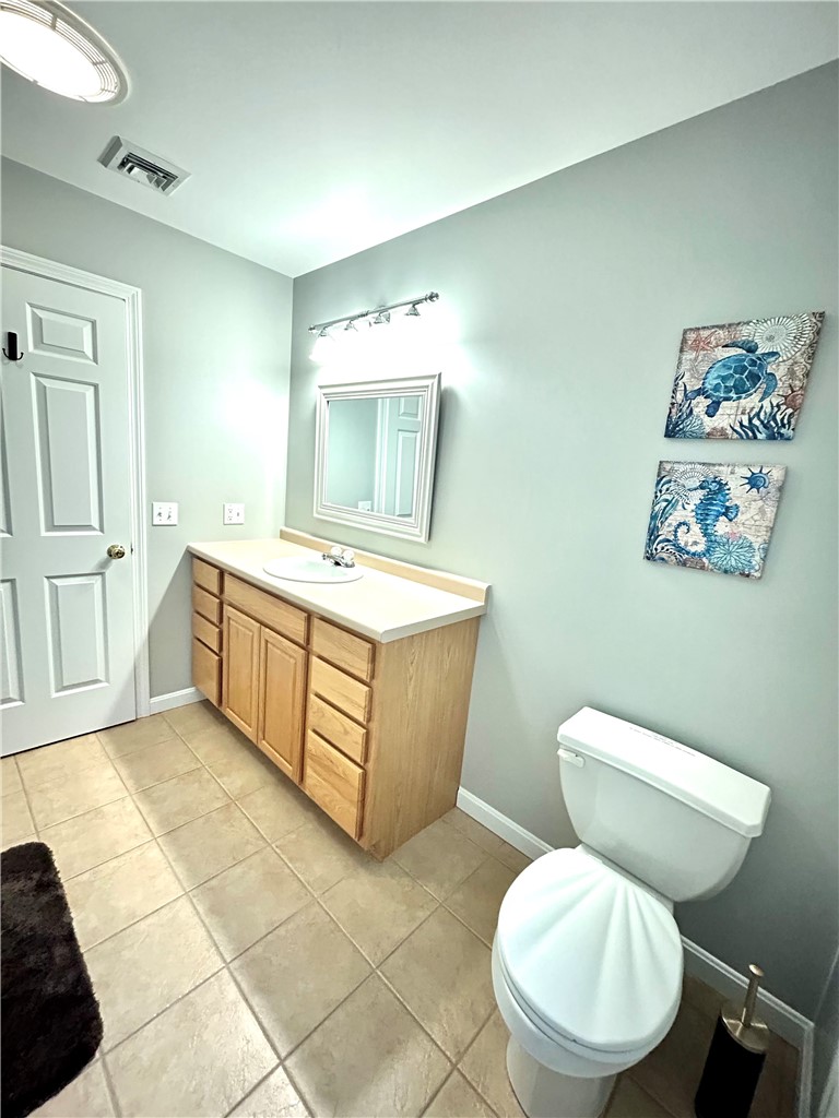 Bathroom with a light wood vanity, beige tile floor, and blue sea-life wall art.