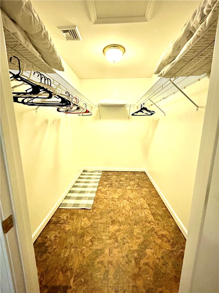 Walk-in closet with wire shelving, hanging rods, and a small rug.