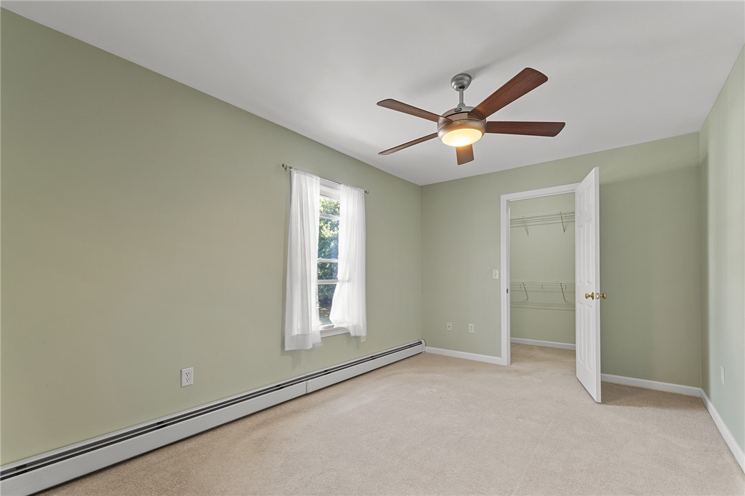 Empty bedroom with pale green walls, beige carpet, and an open closet.