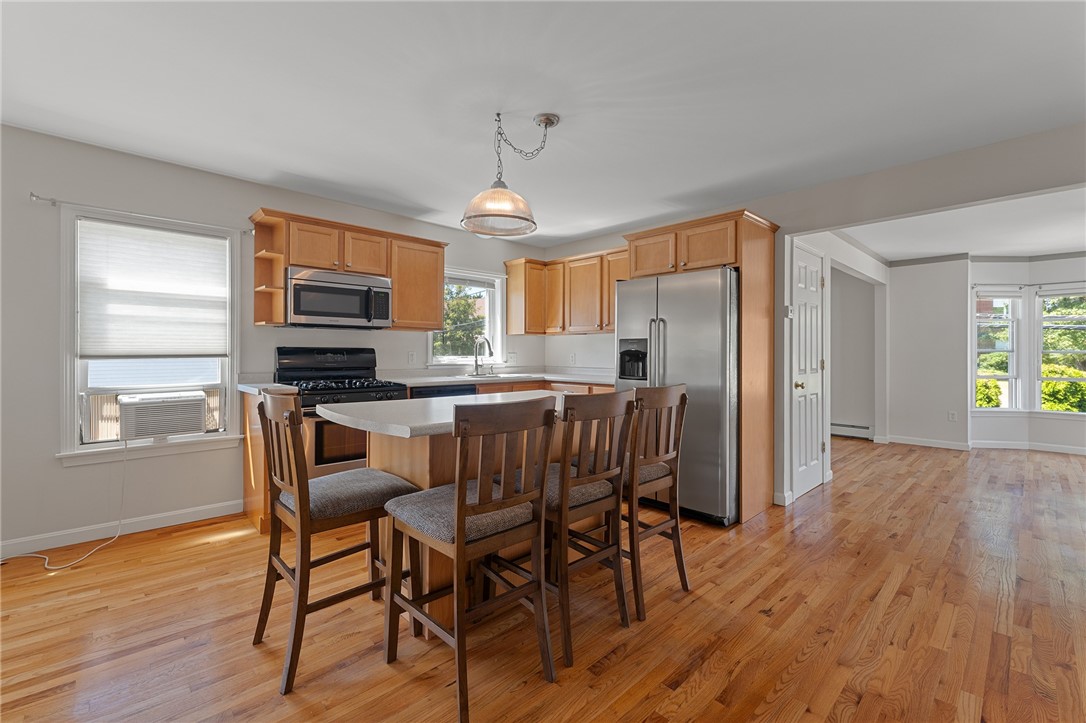 Kitchen with a breakfast island, wood cabinetry, stainless steel appliances, and hardwood floors.