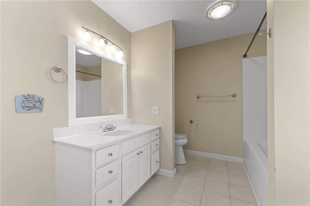 Bathroom with a white vanity and large mirror, toilet, and bathtub.
