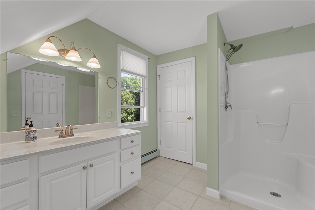 Bathroom with a long white vanity, sage-green walls, and a white shower enclosure.