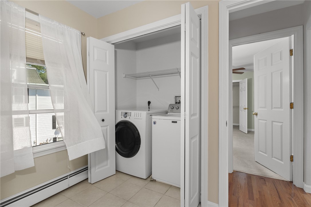 Laundry room with washer and dryer in an open closet beside a curtained window.