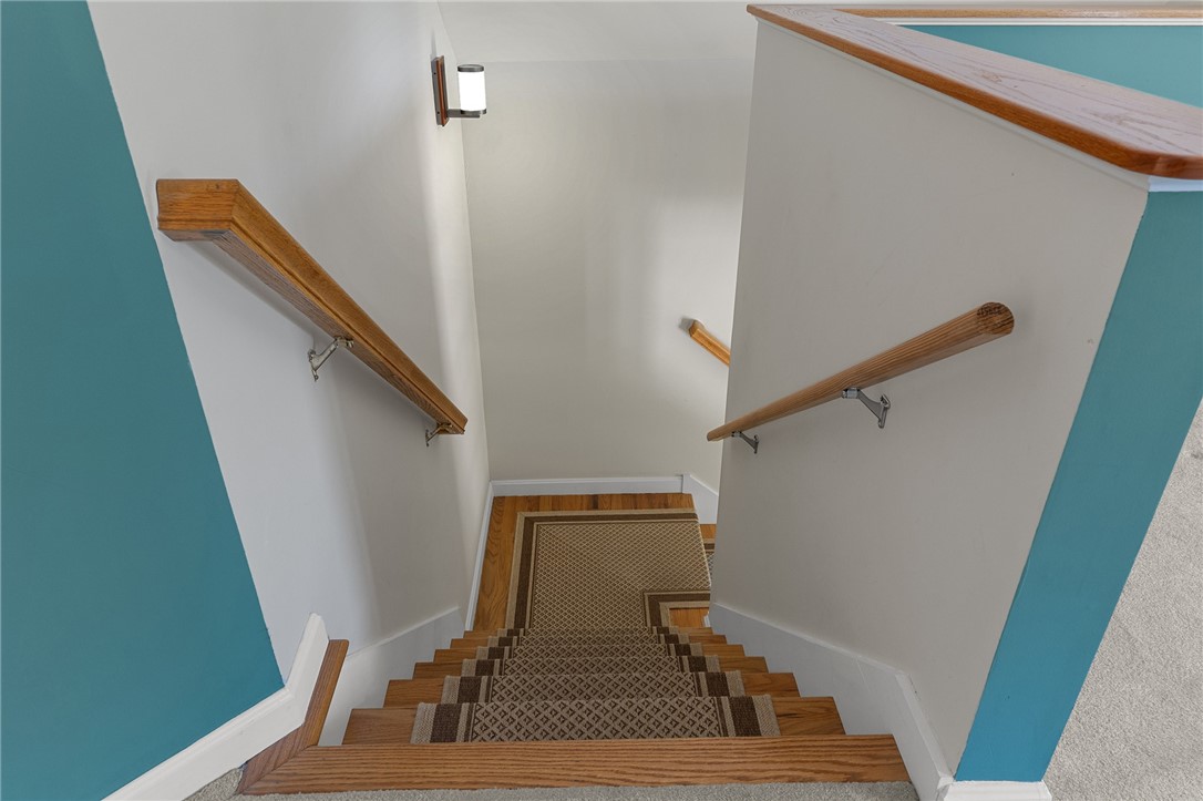 Staircase with a patterned carpet runner, wooden handrails, and teal accent walls.