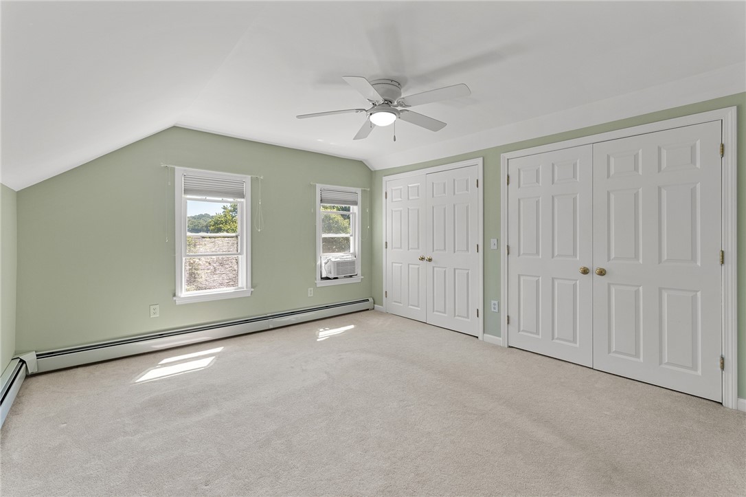 Vacant bedroom with pale green walls, beige carpet, and white paneled closet doors.