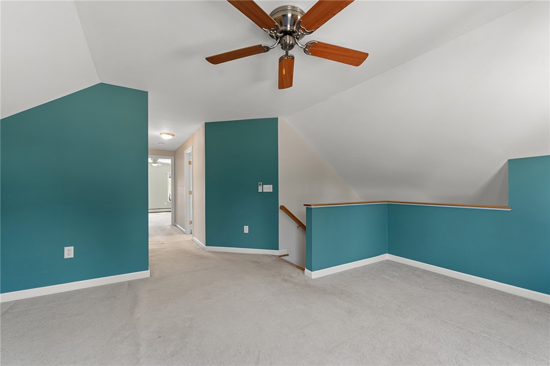 Unfurnished upper-level room with teal walls, sloped ceiling, ceiling fan, and carpet.