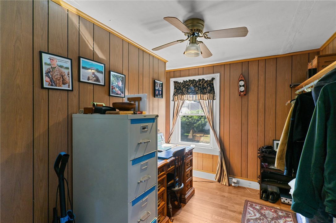 Wood-paneled office with a desk beneath a curtained window and a large filing cabinet.