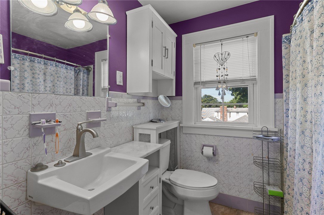 Bathroom with purple walls, patterned tile, a white sink, and a window above the toilet.