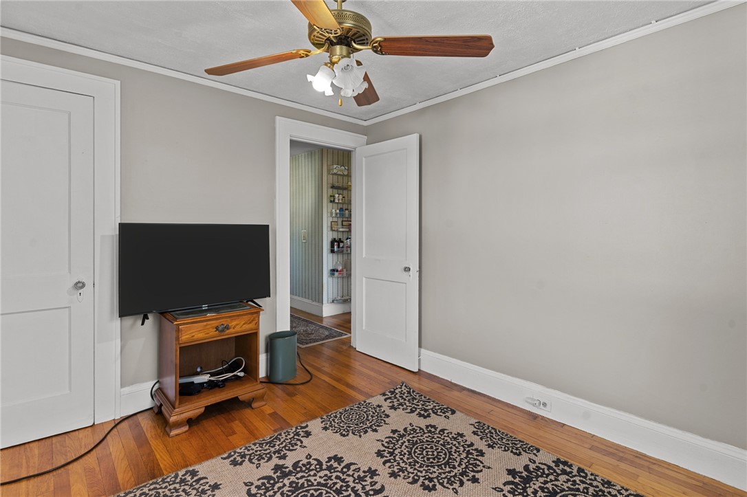 Room with a television on a wooden stand, patterned rug, and hardwood floors.