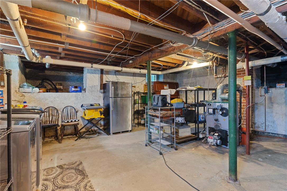 Unfinished basement with exposed pipes, utility equipment, and storage shelving.