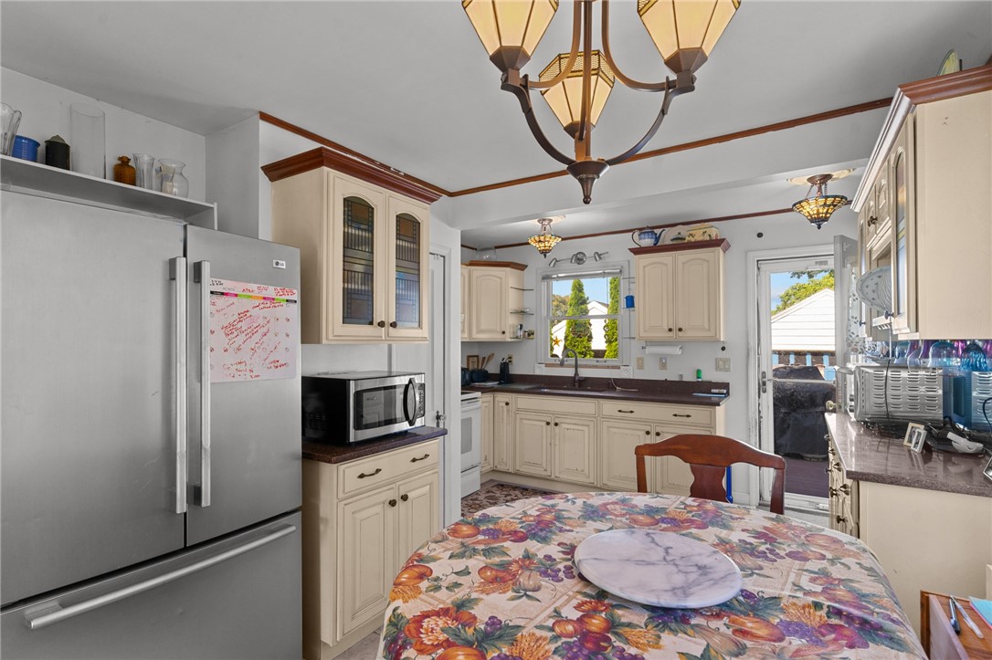 Kitchen with cream cabinets, stainless steel appliances, dark countertops, and a floral-covered table.