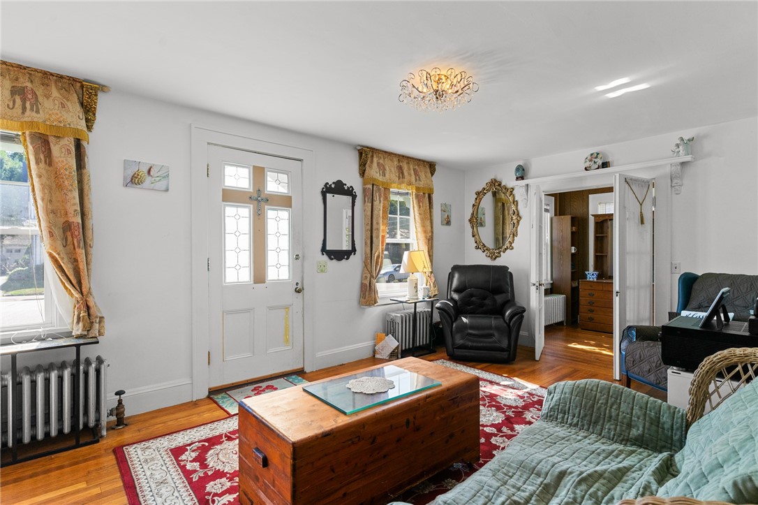 Living room with hardwood floors, a red patterned rug, and a wooden trunk coffee table.