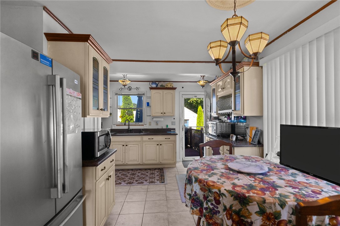Kitchen with cream cabinets, stainless steel refrigerator, and a floral-covered dining table.