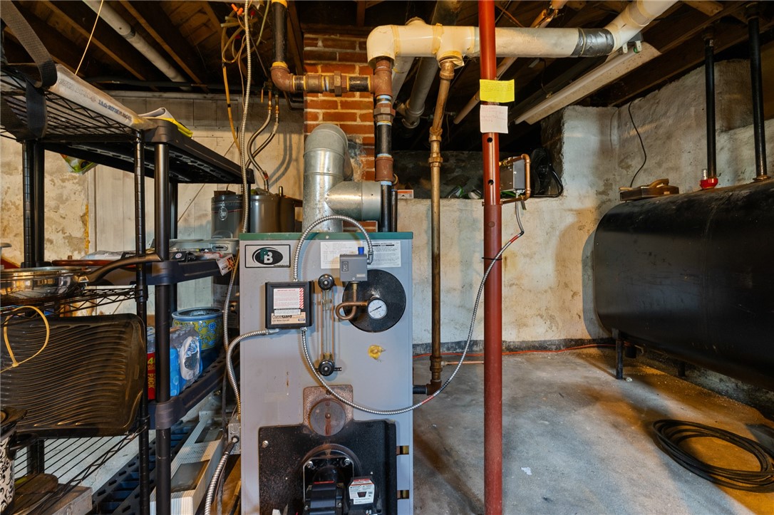 Basement utility room with a boiler, exposed pipes, and a large storage tank.