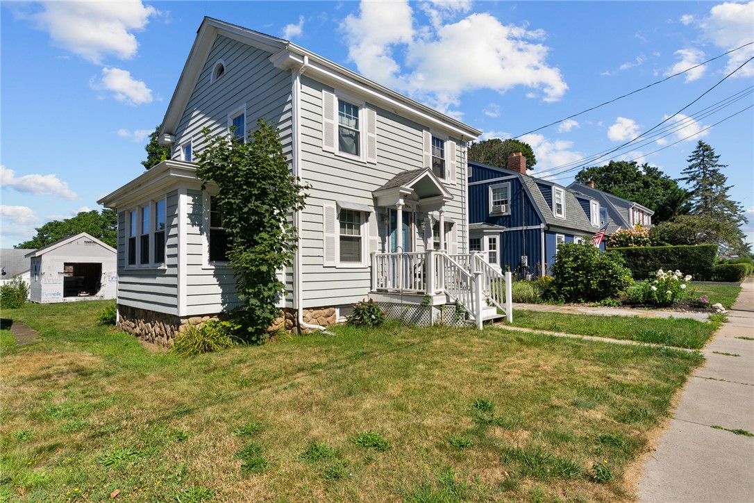 Two-story light-gray house with white trim, a covered entry, and a front lawn.
