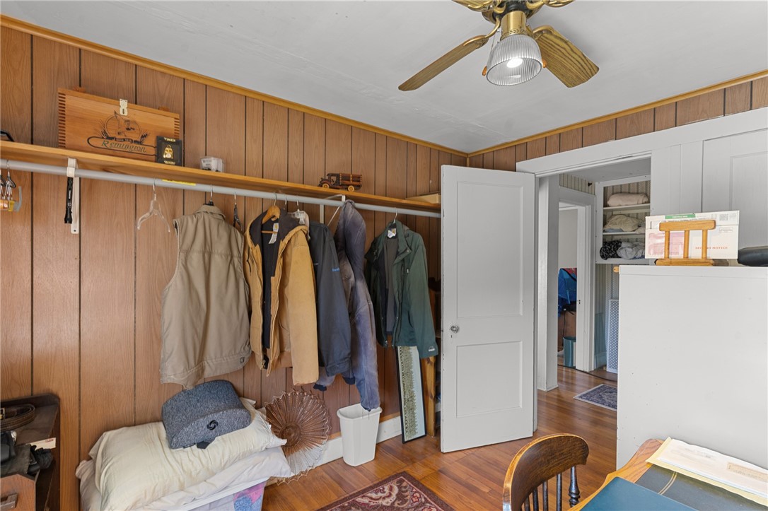 Wood-paneled room with a coat rack, open closet, and ceiling fan.