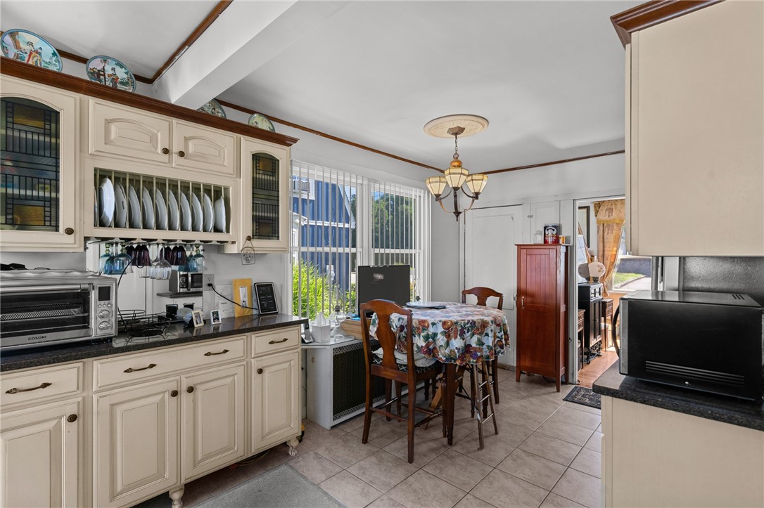 Kitchen with cream cabinets, dark countertops, and a small dining table beside large windows.