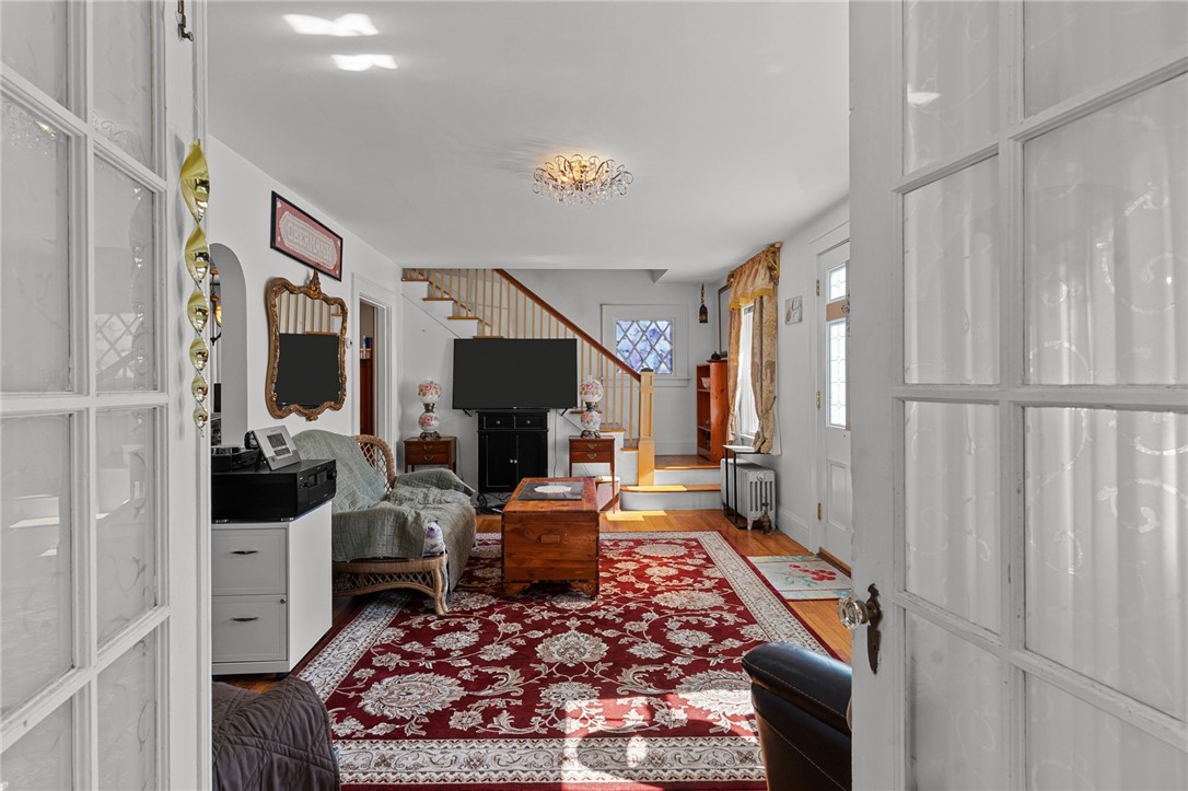Living room with a red patterned rug, wood coffee table, and staircase behind the television.