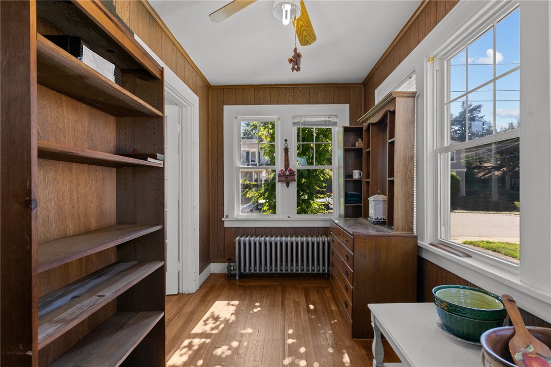 Wood-paneled study with built-in shelves, cabinetry, and large sunlit windows.