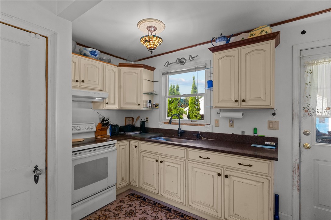 Kitchen with cream cabinets, dark countertops, and a window above the sink.
