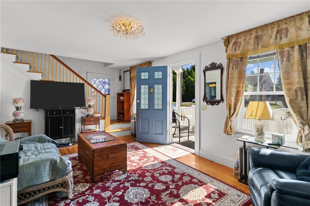 Living room with an open blue front door, staircase, and large window.