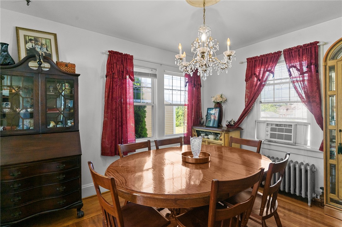 Dining room with a round wooden table, crystal chandelier, and red curtains.
