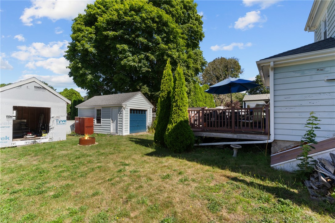 Backyard with a detached garage and raised deck beneath a blue umbrella.