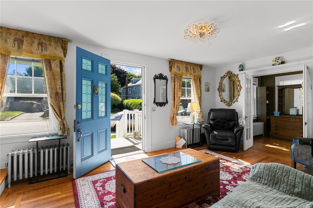 Living room with hardwood floors, a blue open front door, patterned rugs, and traditional furnishings.