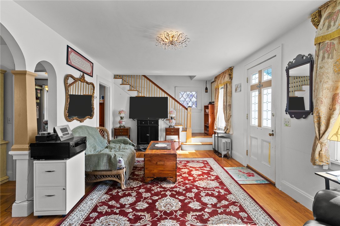 Furnished living room with a red patterned rug, ornate mirrors, and a staircase.