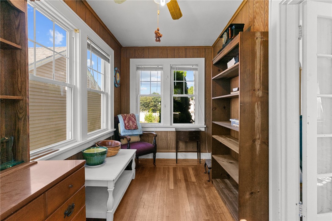 Wood-paneled room with built-in shelves, hardwood floors, and large windows.