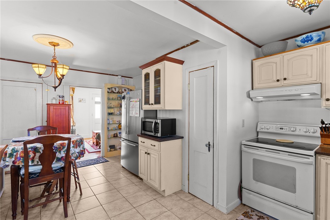 Kitchen and dining area with cream cabinets, stainless steel appliances, and a floral-covered table.