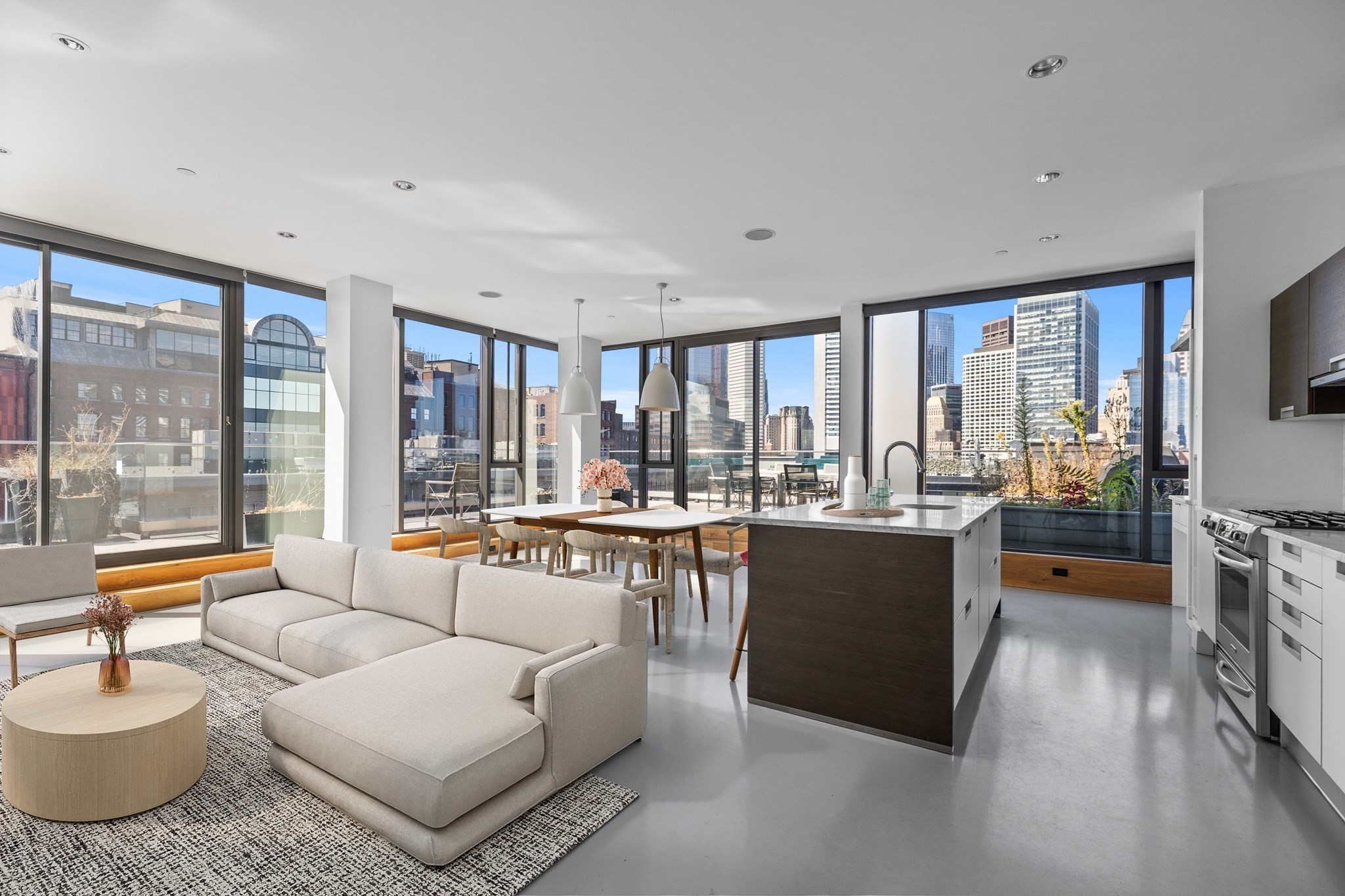 Open-plan condo living room and kitchen with floor-to-ceiling windows overlooking the city skyline.