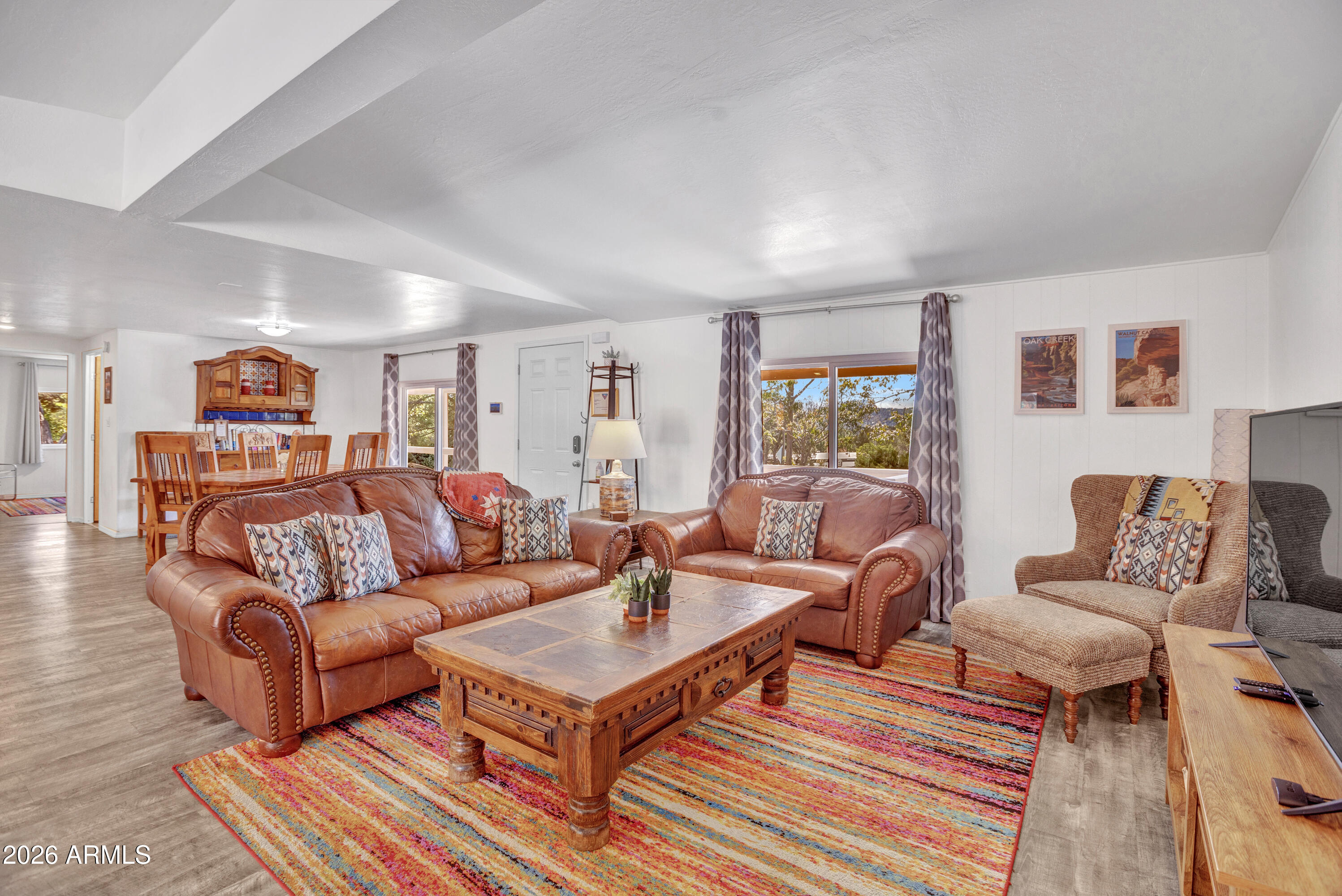 Living room with brown leather sofas, a wooden coffee table, and a colorful striped rug.