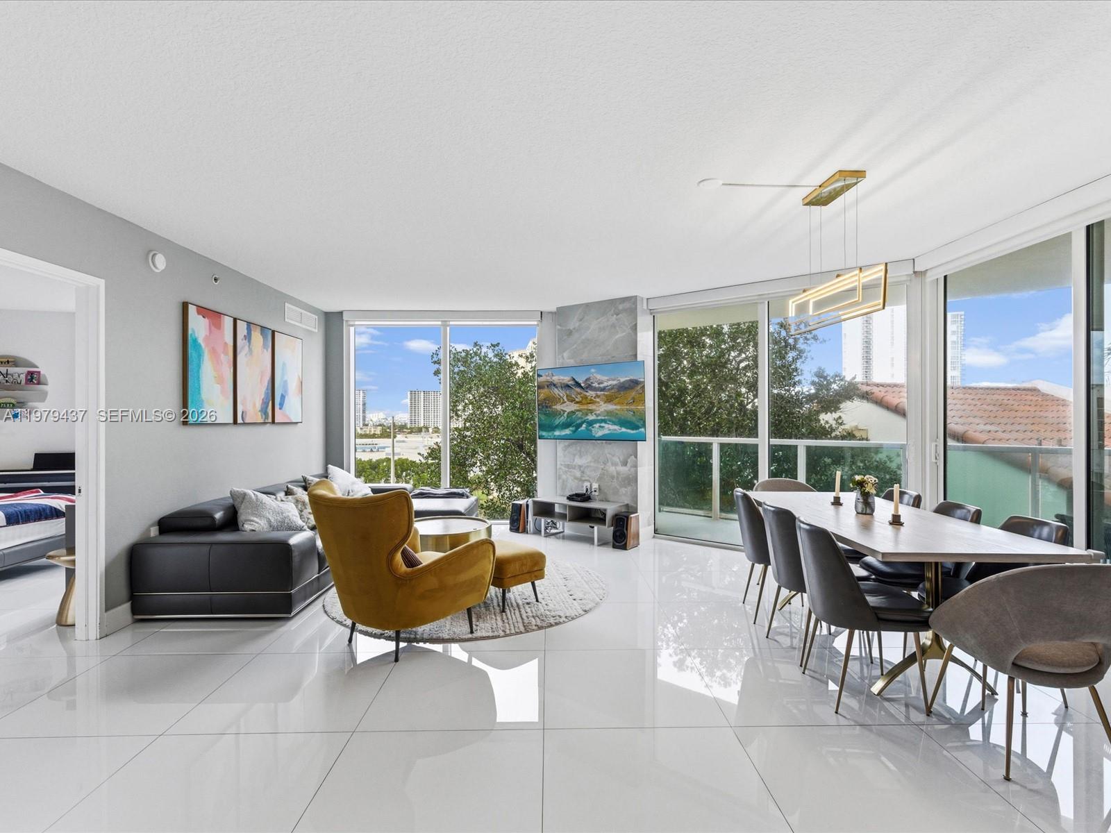 Bright living and dining area with floor-to-ceiling windows and glossy white tile floors.
