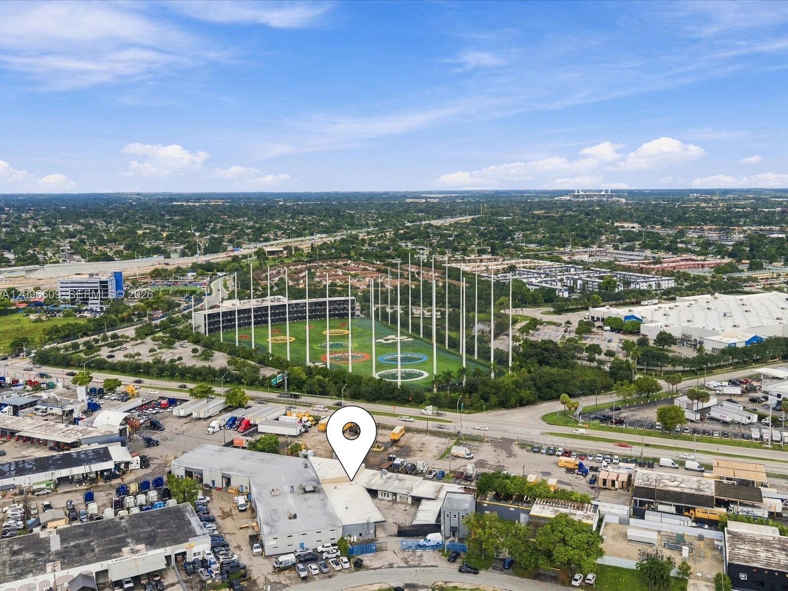 Aerial view of an industrial property marked by a pin, near warehouses and a baseball field.