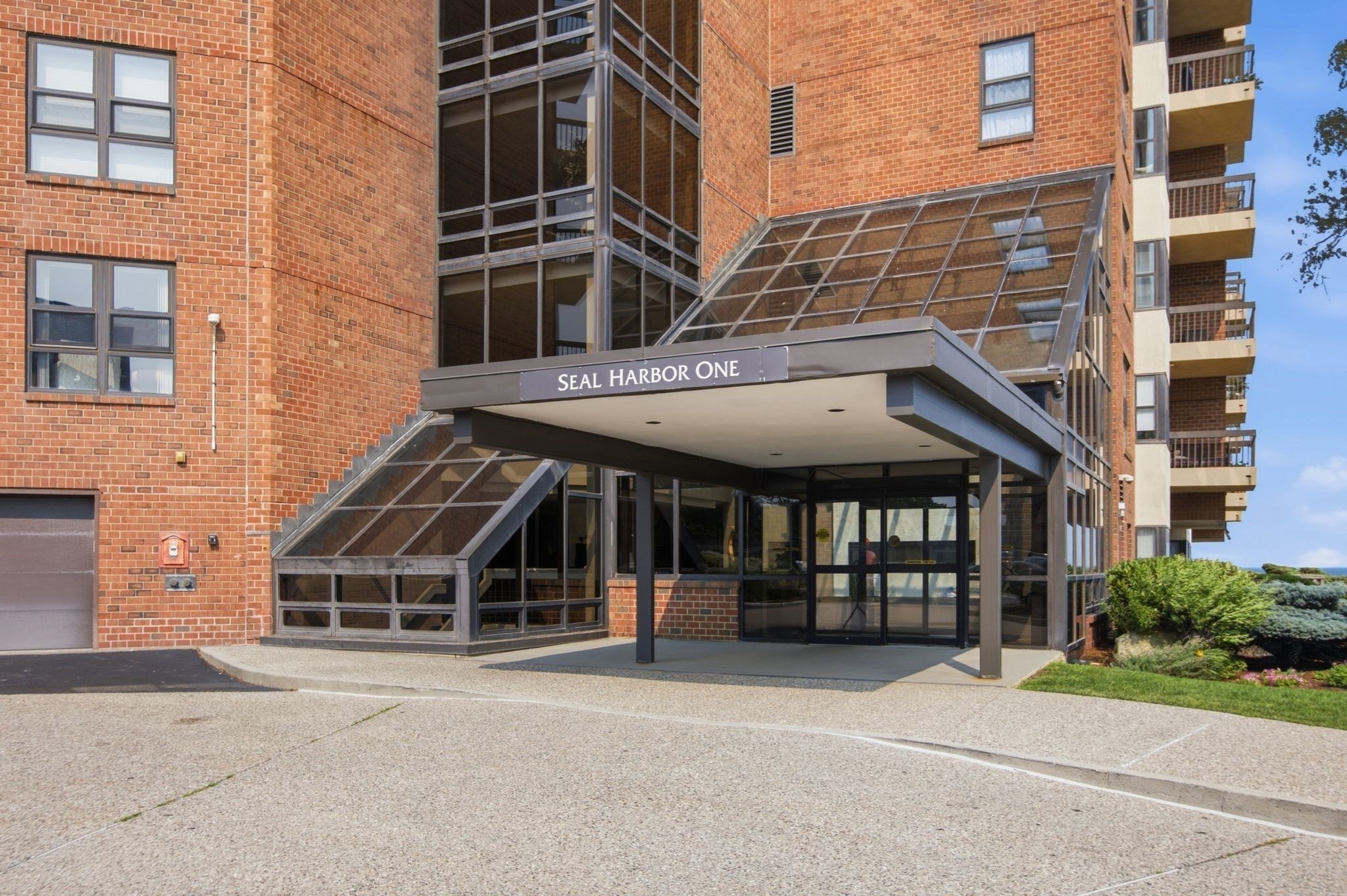 Seal Harbor One condominium entrance with a glass canopy and balconies.
